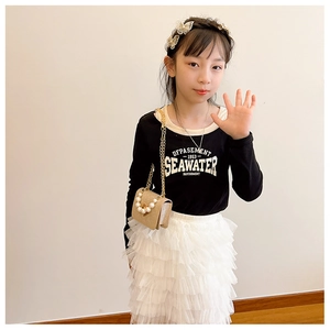 Petite fille portant un sac à main tissé avec perles et chaîne dorée style princesse