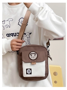 Detail van een bruine en beige canvas crossbodytas met berenpatch en brede schouderriem