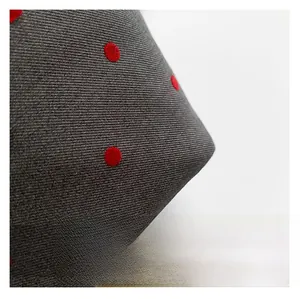 Dettaglio macro del tessuto twill grigio scuro con ricamo a pois rossi in rilievo