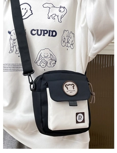 Detailweergave van de zwart-witte canvas crossbody tas met verstelbare riem en berenpatch