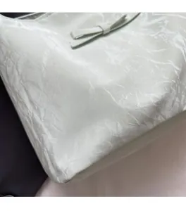 Détail du sac cabas vert menthe avec texture de tissu plissé et décoration de nœud en cuir