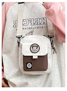 Detail van de kleine beer-patch en D-logo op de wit-bruine crossbody tas van canvas materiaal