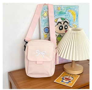 Detailed view of pink canvas crossbody bag featuring white bow embroidery and wide strap