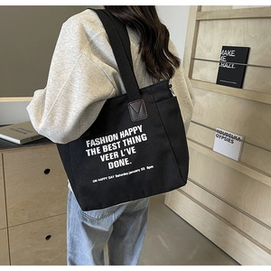 Close-up of black canvas tote bag featuring white inspirational text print on thick material
