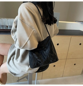 Détail du sac cabas plissé noir avec nœud décoratif porté à l'épaule pour un look décontracté