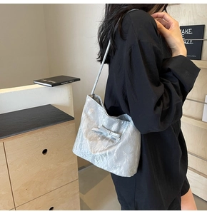 Détail d'un sac cabas argenté avec texture froissée métallique et nœud élégant