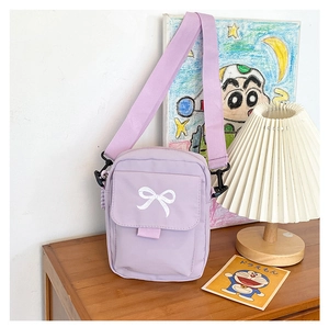 Detail of lavender canvas crossbody bag featuring white bow embroidery and strap