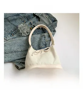 Detail of cream white hobo bag with herringbone fabric texture and bow tie decoration