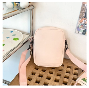 Detail of peach pink fabric crossbody bag with wide shoulder strap and black buckle