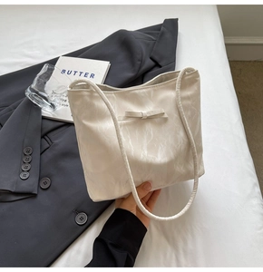 Détail d'un sac cabas crème avec nœud et finition texturée dans un cadre lifestyle