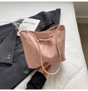 Détail du sac cabas rose brillant avec un nœud décoratif et une texture plissée