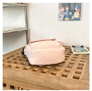 Detailed view of pink fabric crossbody bag side and base on a wooden table