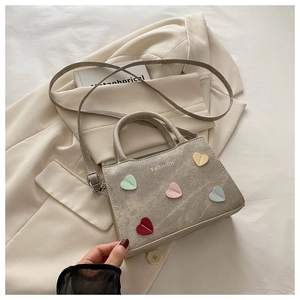 Detail of grey crossbody bag with colorful quilted hearts and white fashion text