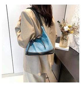 Detailed view of the denim and black leather patchwork tote bag with a bow accent