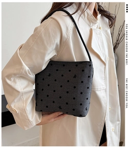 Detailed close-up of grey canvas shoulder bag with black polka dots and bow embroidery