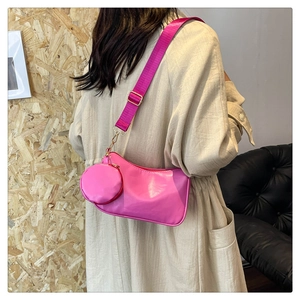Dettaglio della borsa a tracolla rosa con mini pochette e tracolla larga su modella