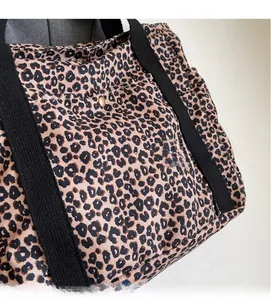 Close-up of leopard print canvas tote bag with black straps and metal snap button