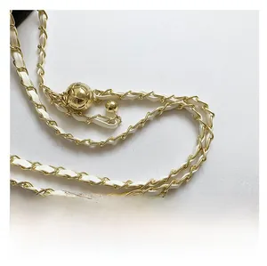 Détail de la chaîne dorée tressée de cuir blanc avec une boucle à bille dorée ajustable