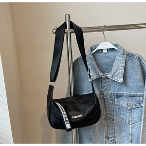 Détail du sac dumpling en cuir grainé noir avec sangle HOMME+FEMME sur présentoir