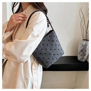 Detail of gray polka dot shoulder bag with bow embroidery and slim black strap