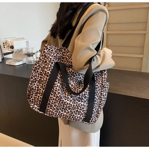 Detailed back view of a large leopard print tote bag with black woven straps on a model