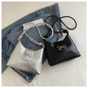 Detail of silver and black glossy shoulder bags with metallic bow buckle and side knot decoration