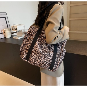 Detail of leopard print tote bag featuring black wide strap and metal snap button closure