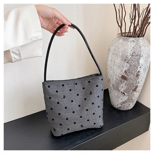Detailed view of gray polka dot tote bag with bow knot patterns on black wooden surface