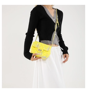 Détail de sac matelassé jaune avec broderie colorée et fermoir métallique brillant