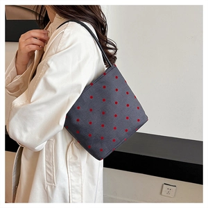 Close-up of a dark grey polka dot bag showing shoulder wear with red patterns
