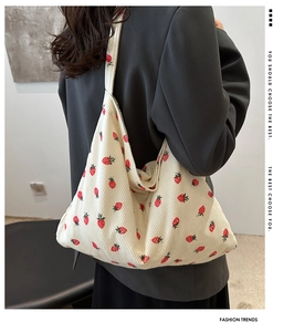 Détail du sac cabas en velours côtelé blanc cassé avec imprimé fraise porté à l'épaule