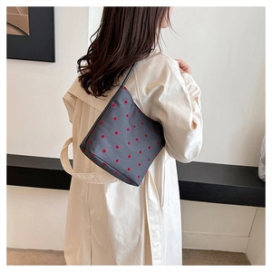 Detail of grey polka dot shoulder bag showing its trapezoidal shape and slim strap