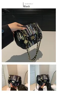 Détail du sac bandoulière noir matelassé avec broderies et bandoulière chaîne dorée