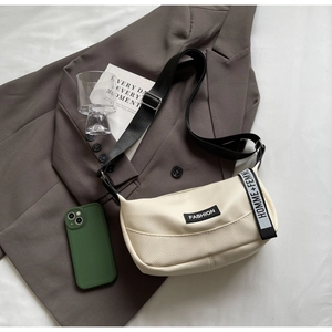 Détail du sac beige en cuir grainé avec logo Fashion et bandoulière textile lettrée