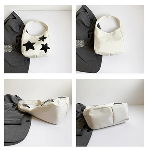 Detailoverzicht van de gebroken witte canvas tas met zwarte sterren en een brede schouderriem