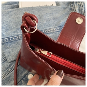 Detail view of the deep reddish-brown leather bag showing interior zipper pocket and stitching