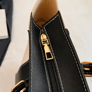 Detail shot of smooth golden zipper and white contrast stitching on the shoulder bag