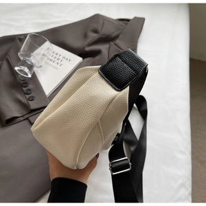 Détail du sac bandoulière bicolore crème et noir avec texture cuir litchi grainé