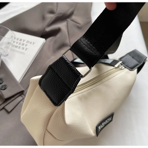 Gros plan d'un sac hobo en cuir beige avec bordure noire et étiquette mode élégante