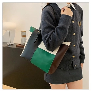 Detail of color-block tote bag in dark green and beige worn by model on shoulder
