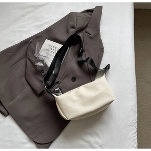 Détail du sac ivoire avec texture lychee, bandoulière noire large et boucle métal