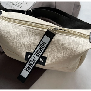 Gros plan du sac en cuir grainé crème avec étiquette et bandoulière en nylon