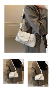 Detalle de bolso bandolera blanco con lazo decorativo y cadena de flores plateada