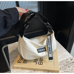 Détail du sac bandoulière blanc motif litchi avec sangle large et pendentif de mode