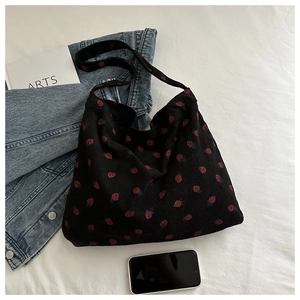 Détail du sac cabas en velours côtelé noir avec imprimé fraise rouge et texture douce