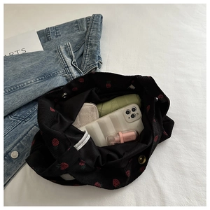 Vue intérieure d'un sac cabas en velours côtelé noir avec broderie fraise et accessoires