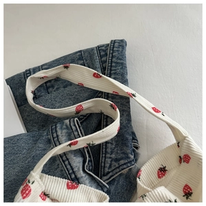 Gros plan du sac fourre-tout en velours côtelé blanc avec imprimé fraises sur un jean