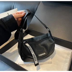 Vue détaillée d'un sac bandoulière en cuir grainé noir présenté dans un coffret cadeau chic