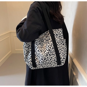 Detail of leopard print tote bag featuring black canvas strap and side pocket on the shoulder