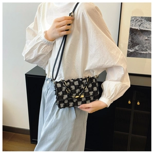 Détail d'un sac bandoulière tissé à damier avec franges et bandoulière dorée